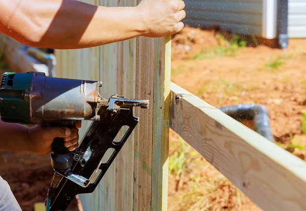 man contructs portions of wooden fence